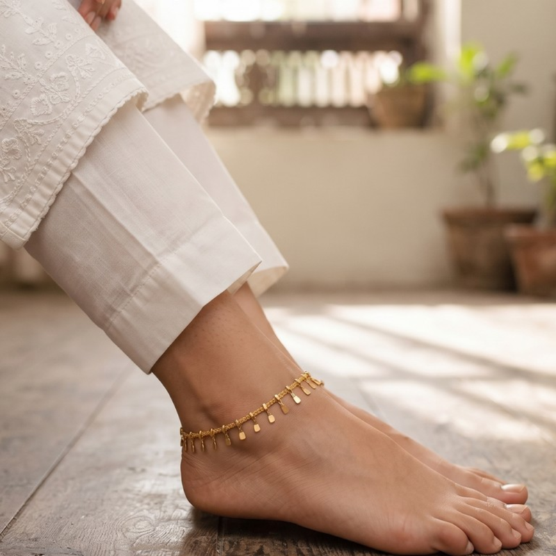 Model in Pakistan wearing the Dango IP gold plated stainless steel drop anklet around the ankle with no other jewelry.