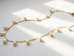Dango 18K gold plated chain necklace with dangling freshwater pearls resting on a white background.