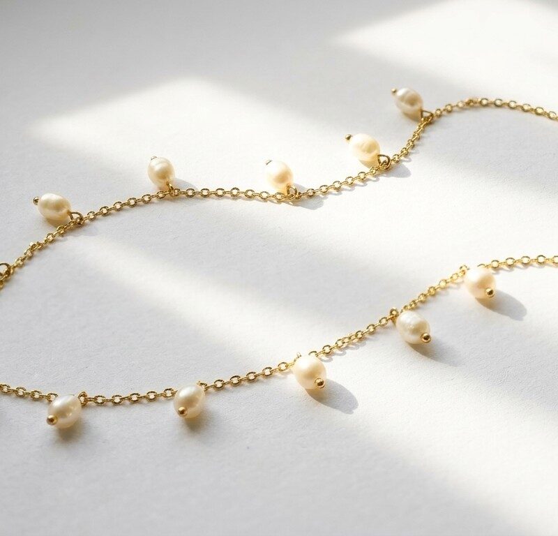 Dango 18K gold plated chain necklace with dangling freshwater pearls resting on a white background.