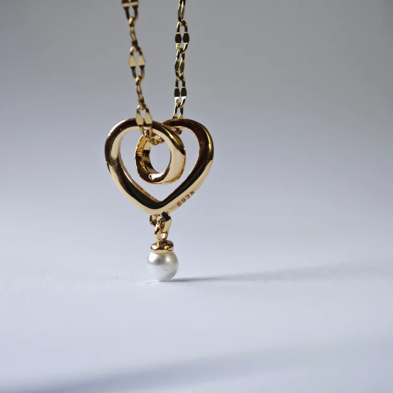 Dango gold plated stainless steel chain with a 10mm plated copper interlocking heart and pearl pendant, displayed against a clean background in Pakistan.