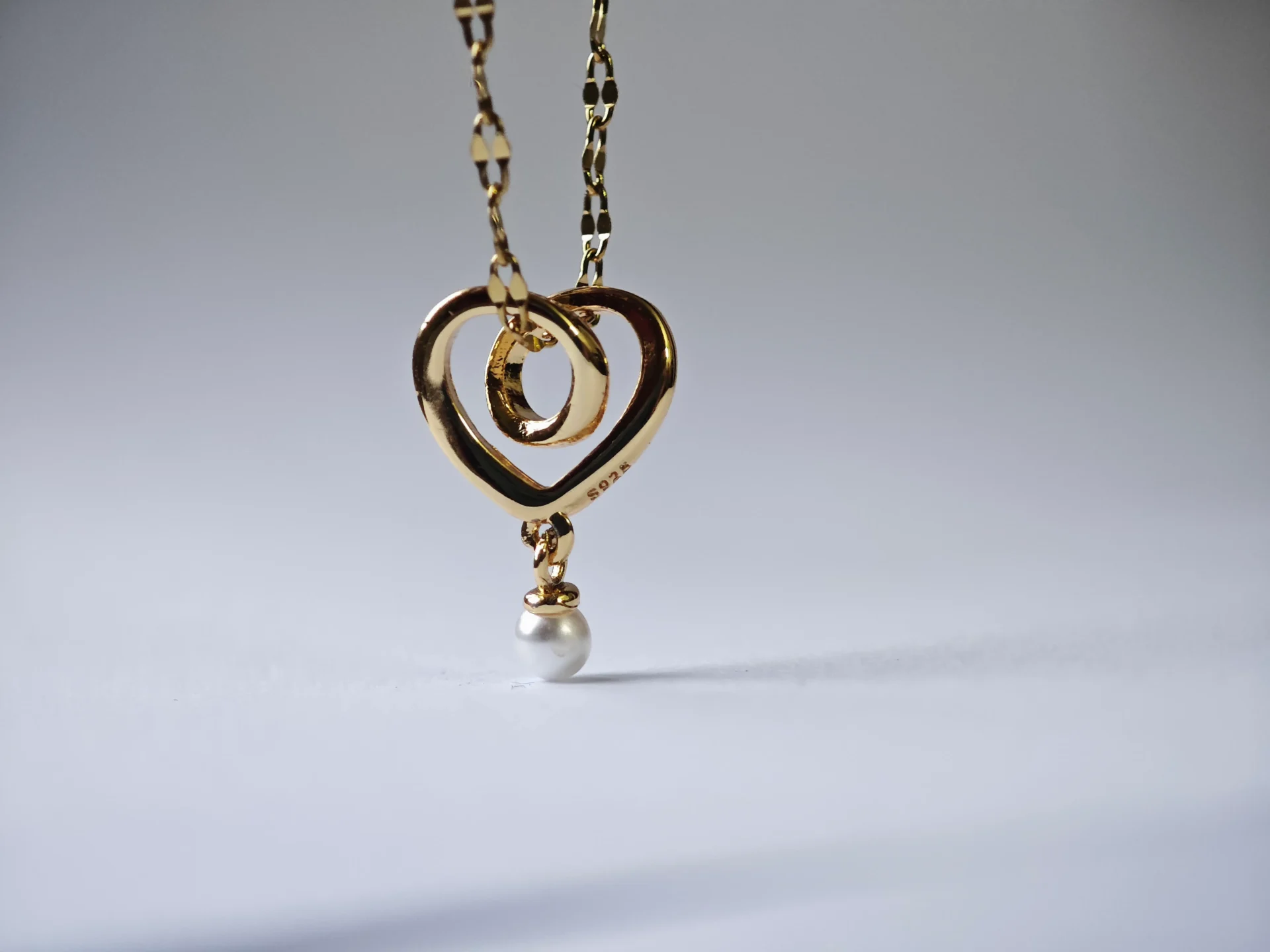 interlocking heart pendant Dango gold plated stainless steel chain with a 10mm plated copper interlocking heart and pearl pendant, displayed against a clean background in Pakistan.