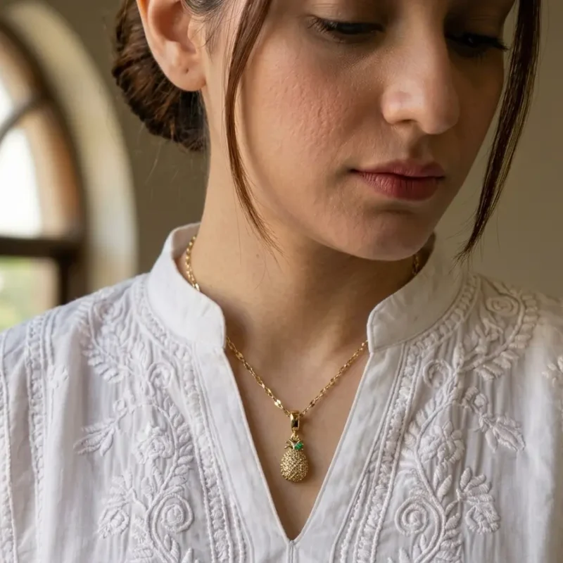 Model in Pakistan wearing the Dango gold plated crystal pineapple pendant necklace against her neckline.