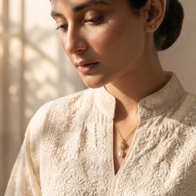 Model in Pakistan wearing the Dango gold plated seashell and freshwater pearl pendant necklace against her neckline.