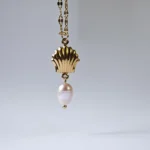 Dango gold plated stainless steel PVD chain with a 7mm seashell charm and dangling freshwater pearl, displayed against a clean background in Pakistan.