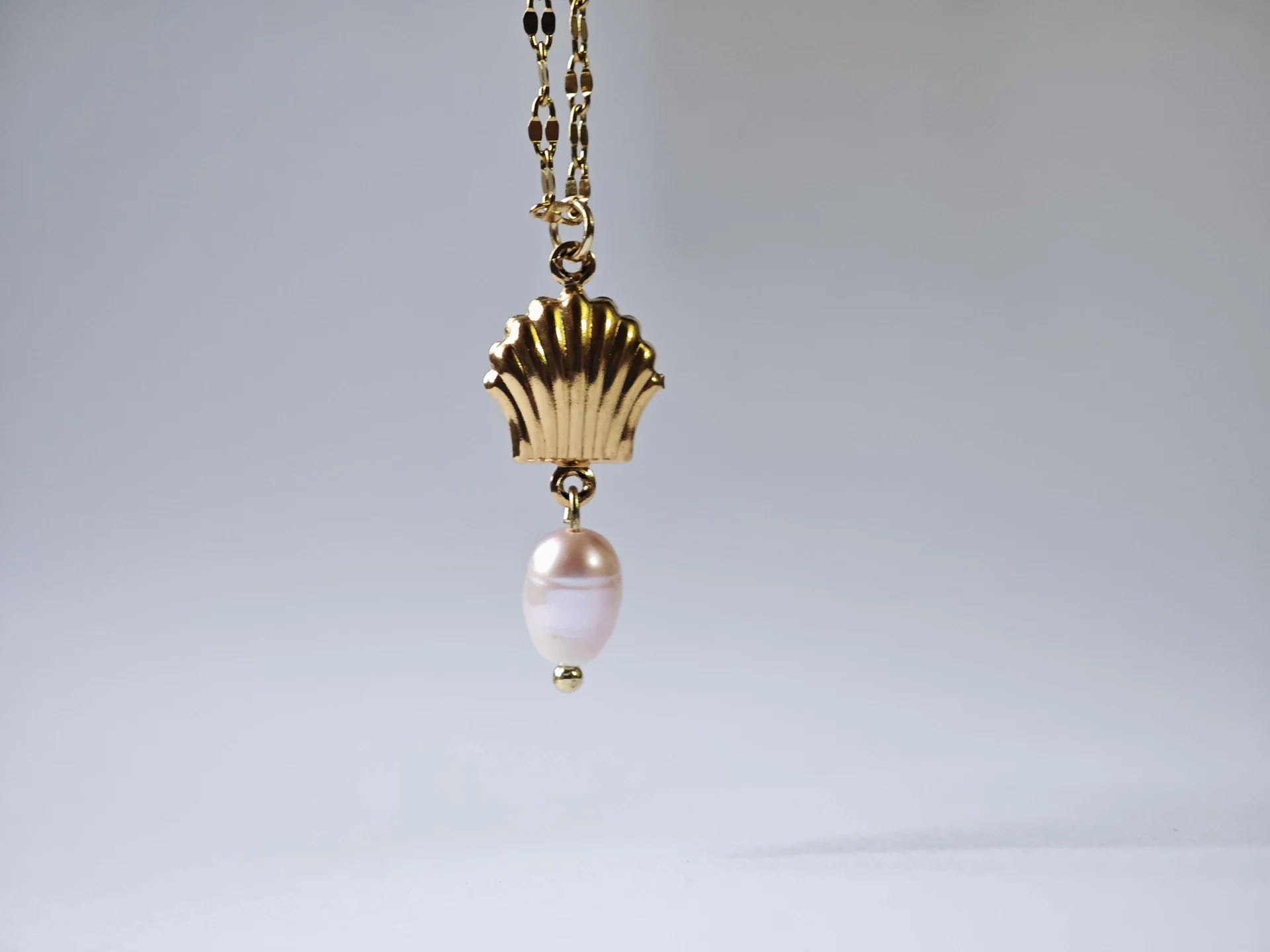 shell and pearl1 Dango gold plated stainless steel PVD chain with a 7mm seashell charm and dangling freshwater pearl, displayed against a clean background in Pakistan.