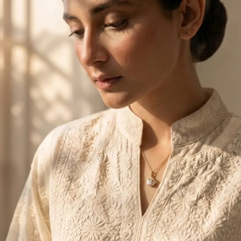 Model in Pakistan wearing the Dango gold plated white enamel fish pendant necklace against her neckline.