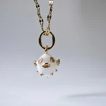 Dango gold plated steel chain necklace featuring a glossy white enamel pufferfish pendant with sparkling zircon details, displayed on a neutral background in Pakistan.