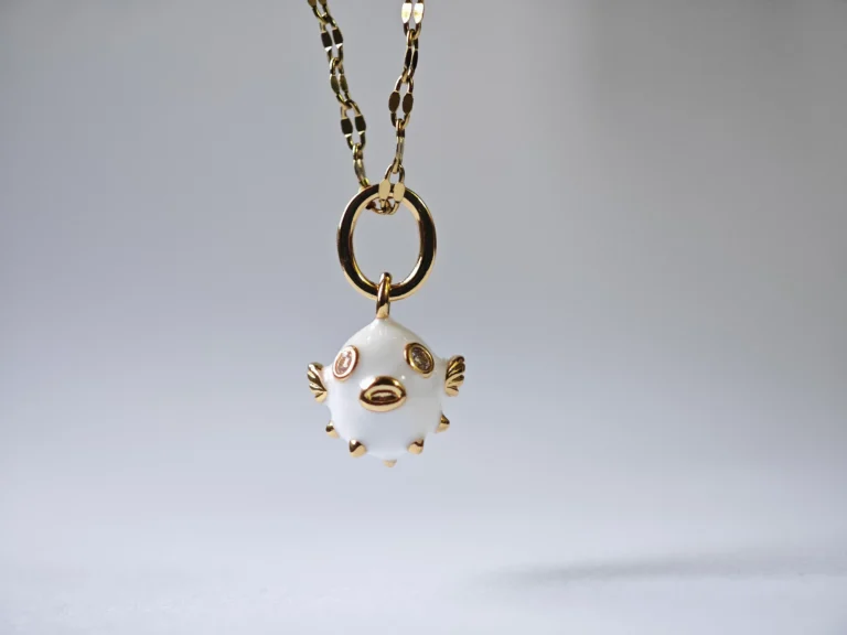 Dango gold plated steel chain necklace featuring a glossy white enamel pufferfish pendant with sparkling zircon details, displayed on a neutral background in Pakistan.